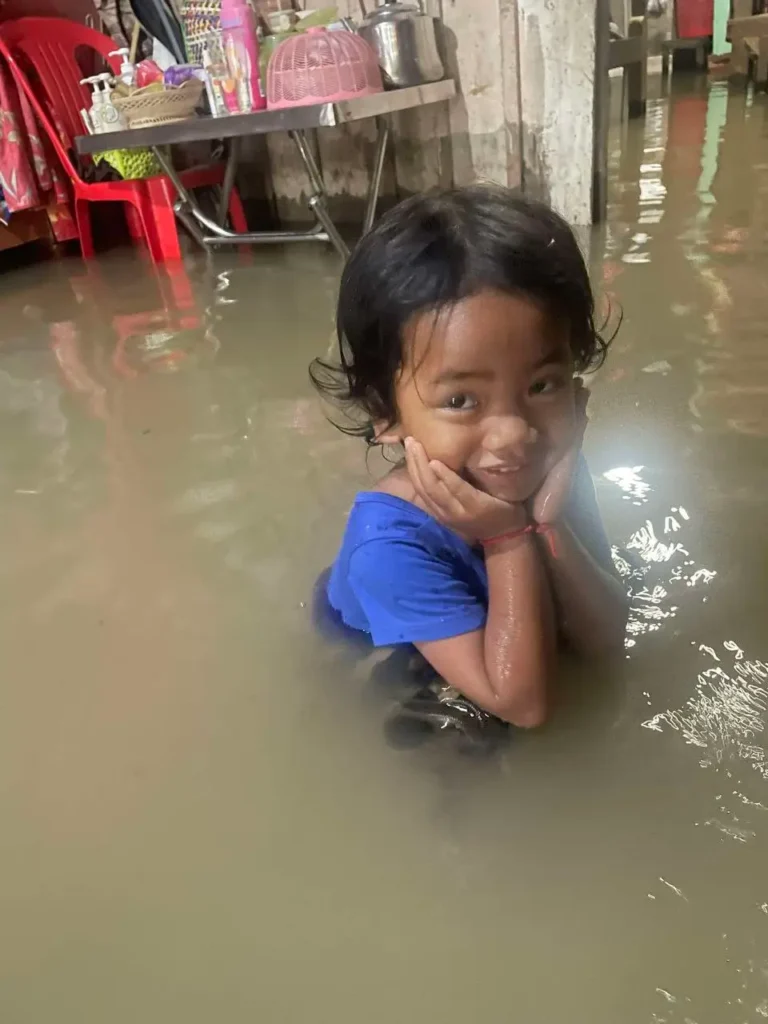 Flooded interior of a Phnom Penh family home during heavy rain, highlighting urgent housing needs